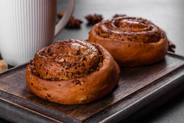Freshly baked cinnamon roll with spices and cocoa filling on a black background
