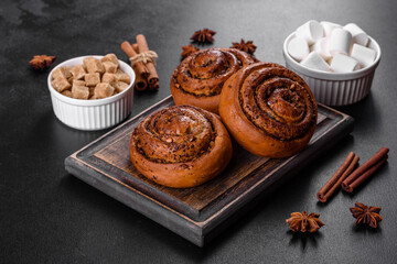 Freshly baked cinnamon roll with spices and cocoa filling on a black background