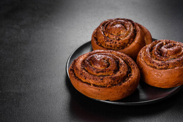 Freshly baked cinnamon roll with spices and cocoa filling on a black background