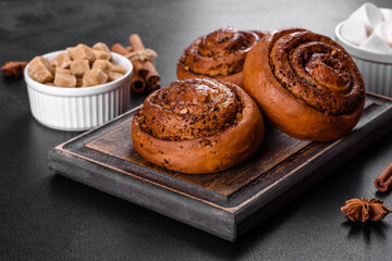 Freshly baked cinnamon roll with spices and cocoa filling on a black background