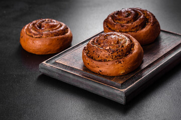 Freshly baked cinnamon roll with spices and cocoa filling on a black background