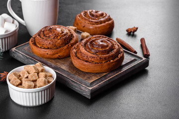 Freshly baked cinnamon roll with spices and cocoa filling on a black background