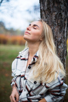 Caucasian Young Blonde Woman In White Flannel Shirt In The Autumn Park