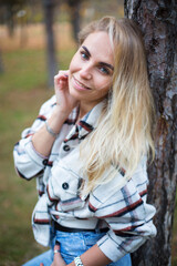 Naklejka premium caucasian young blonde woman in white flannel shirt in the autumn park