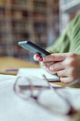 Close-up: the girl's hands with bright manicure are holding a smartphone and typing a message.