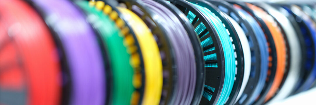 Closeup of spools with multi-colored plastic wires for 3D printers
