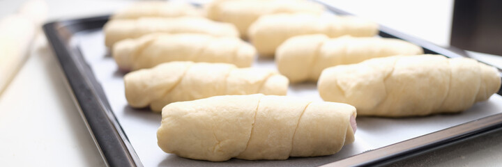 Fototapeta na wymiar Lots of uncooked puff pastry buns on baking sheet closeup