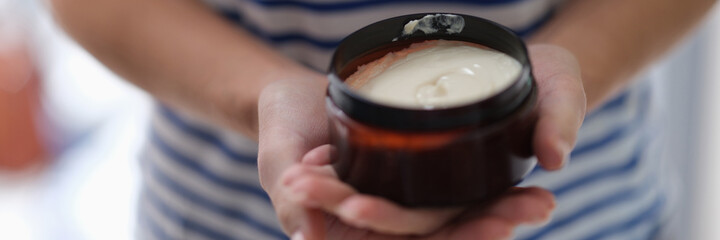 Female hands holding jar of hair mask closeup