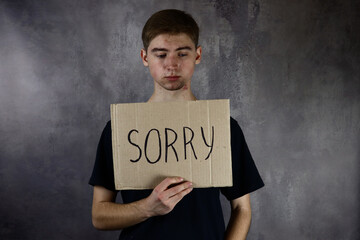 Guy holding a paper with the word Sorry