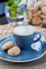 Delicious fresh white coffee in the elegant blue cup and Italian amaretti biscuits in Italian cafe.