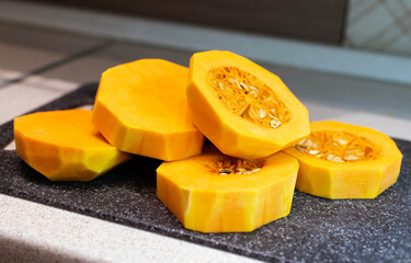 Sliced pumpkin on a cutting board in the kitchen. Background of the process of cooking American pumpkin pie