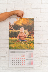 men's hand holds calendar with photo of child in front of. printed products
