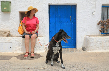 mujer turista con perro negro sentada delante de una casa blanca con puerta azul  almería cabo de...