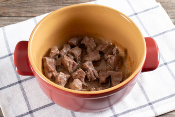 Preparation stewed beef tongue with vegetables close-up in a saucepan on the table. Step by step