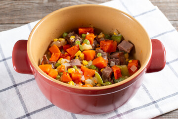 Stewed beef tongue with vegetables in a saucepan on the table. horizontal