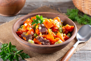 Stewed beef tongue with vegetables in a bowl on the table. horizontal