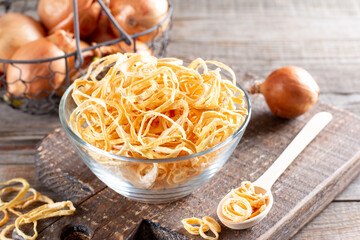 Dried onion rings in a glass bowl on a table. Spices and food ingredients