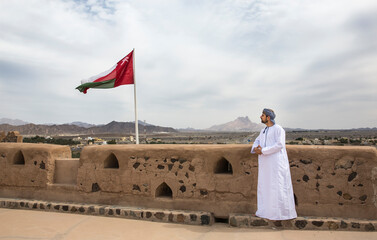 omani man in traditional outfit looking at the landscape of countruside - obrazy, fototapety, plakaty
