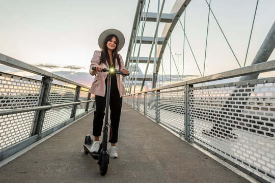 A young girl standing on the bridge next to her electric scooter