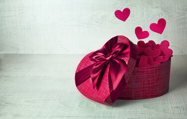 Single red gift box with fireworks from hearts on gray background.