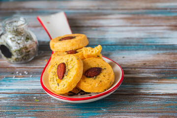 Unsweetened round cheese biscuits with herbs and almonds on a ceramic spoon on a wooden background. Savory cookie recipes as appetizers.