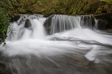 Long exposure of a waterfall flowing through the woods at Watersmeet in Exmoor National Park
