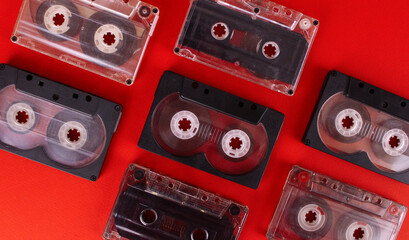 A group of old audio cassettes on a red background. Retro technology