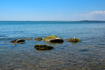 Landscape photo of the sea shore with a bridge in the distance