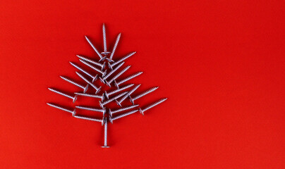 Christmas tree made of self-tapping screws on a red background