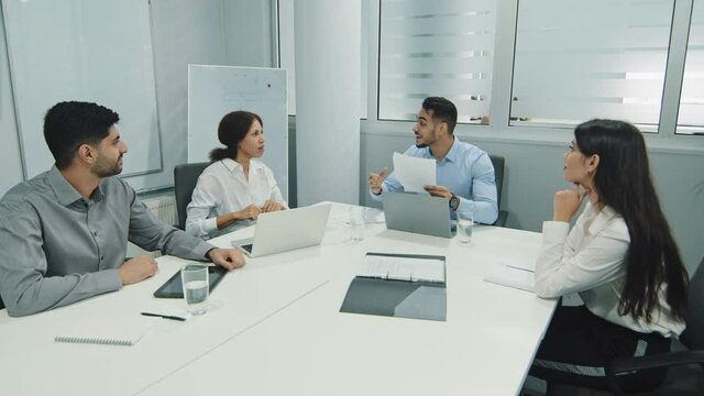 Diverse workers businesspeople working in modern office, sitting together at meeting multiethnic colleagues feels happy, showing team spirit gesture, celebrating news victory goal teamwork achievement