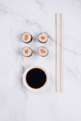 Obraz na płótnie Canvas Classic sashimi with salmon or tuna fish, soy sauce and chopsticks on marble table background - maki sushi roll, nori maki, futomaki. Asian food delivery, online order food concept, sushi bar menu