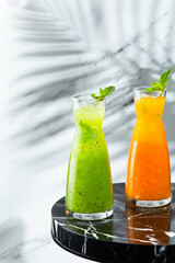 lemonade jug on marble table with copy space on light background. Peach and green lemonade with ice and mint