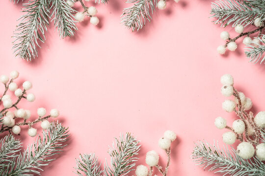 Christmas background with fir tree branches at pink background. Flat lay image with copy space.