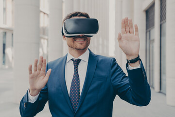 Businessman in suit trying out and experiencing virtual reality using mobile VR headset outdoors