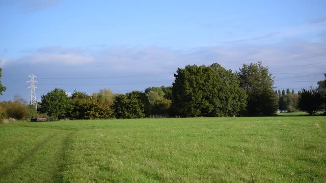 High-voltage power lines in English contryside panoramic view.