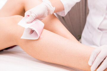 Depilation. Woman getting her legs waxed by beauty therapist in the health spa to make her legs smooth, gentle and clean.