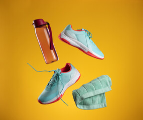 pink plastic water bottle and green towel and pair of textile blue sneakers with laces levitate on...