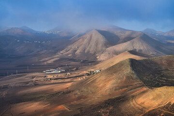 Sunrise in Lanzarote. Trade wind clouds coming over the mountains and dissolve. Canary Islands,...