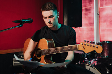Songwriter thinking and writing notes, lyrics on sheets at studio. Concept for musician creative,...