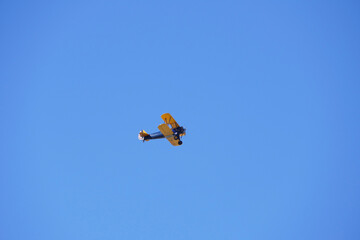 vintage biplane flying high in a bright blue sky