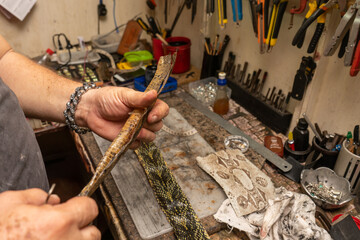 Latin saddler working on handicrafts, belts, bags and wallets on snakeskin leather.