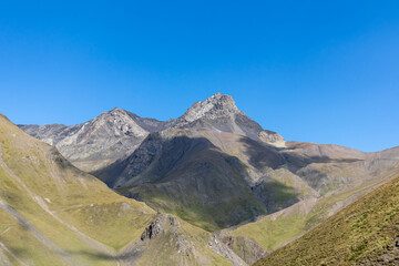 A panoramic view on the sharp ridges of the high mountain peaks of the Chaukhi massif in the Greater Caucasus Mountain Range in Georgia, Kazbegi Region. Wanderlust. Clear Sky. Hiking
