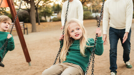 LGBT family - Happy kids and fathers fun swinging on swing at city park - Focus on right boy face