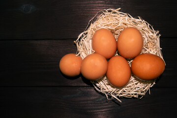 Easter brown eggs in the nest on a dark wooden background