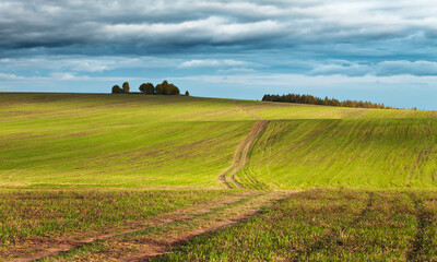Fototapeta na wymiar Gloomy sky over fields, hills and a countryside road