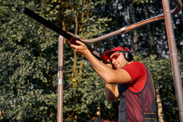 Handsome confident man aiming with hunting rifle in the outer wood. Carbine with optical-sight....