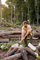 Lumberjack in casual shirt chops tree in deep forest with sharp ax. Brutal muscular male working alone, chopping trees, getting firewood. Side view. caucasian lamberjack in the evening outdoors