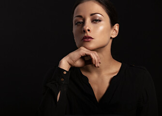Fototapeta premium Business strong thinking woman find the answer in clever mind with fingers near the face in black t-shirt on dark shadow black background. Closeup face portrait.