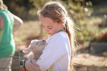 Pretty farm girl holding beautiful baby lamb