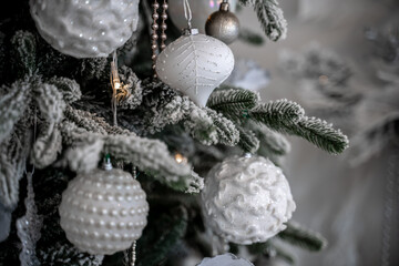 Close-up of a festively decorated outdoor Christmas tree with balls on a blurred sparkling fairy background. Defocused garland lights, bokeh effect.